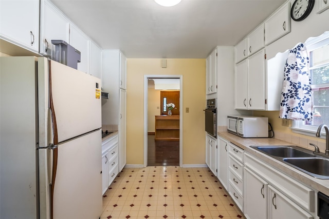 kitchen with white appliances, white cabinetry, and sink