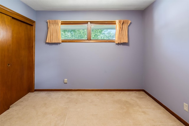 unfurnished bedroom with light colored carpet and a closet