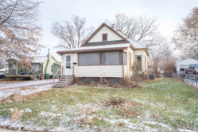 bungalow-style house featuring a front lawn and cooling unit