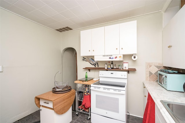 kitchen featuring dark tile patterned flooring, white appliances, white cabinetry, and sink