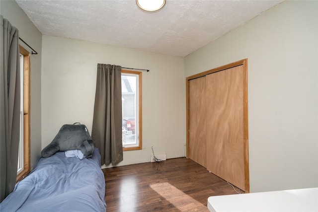 bedroom featuring a closet, dark hardwood / wood-style flooring, and a textured ceiling