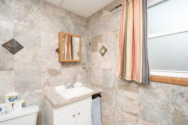 bathroom with vanity, tile walls, and toilet