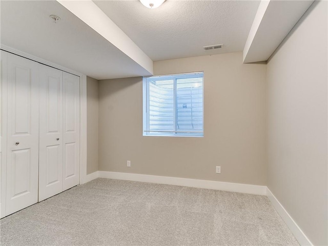 basement featuring light carpet and a textured ceiling