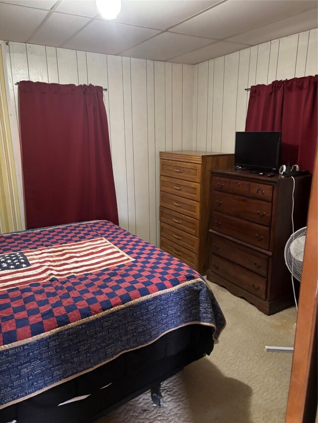 bedroom with carpet flooring and wood walls