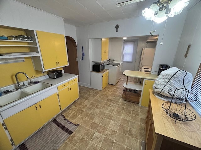 kitchen featuring washing machine and dryer, white fridge, and sink