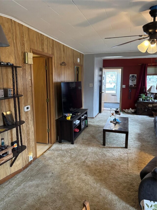 living room with light colored carpet, ceiling fan, and wooden walls