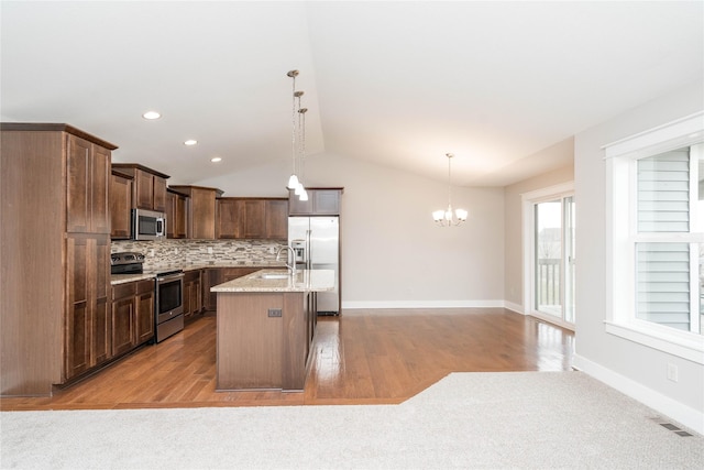 kitchen featuring light wood-type flooring, appliances with stainless steel finishes, a center island, and pendant lighting