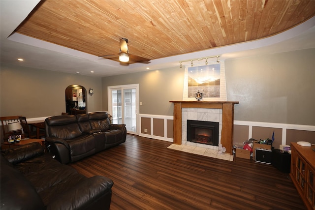 living room featuring ceiling fan, dark hardwood / wood-style flooring, wood ceiling, and a fireplace