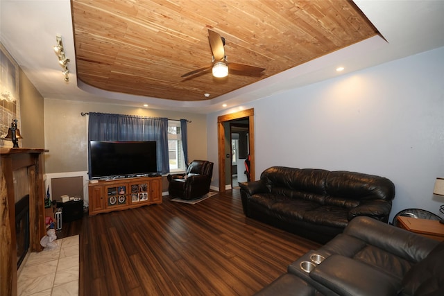 living room featuring ceiling fan, a tile fireplace, a tray ceiling, and wooden ceiling