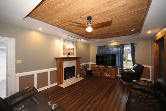 living room featuring wood-type flooring, a tile fireplace, a raised ceiling, and wood ceiling