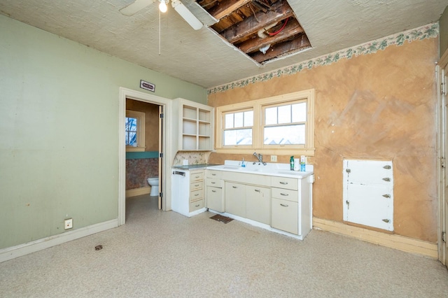 kitchen with white cabinetry, ceiling fan, and sink