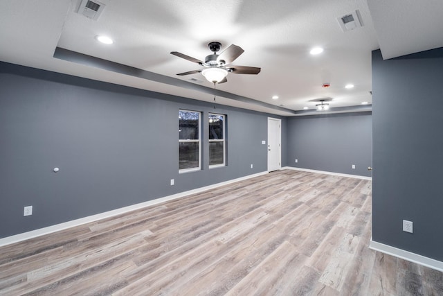 basement featuring ceiling fan, light hardwood / wood-style flooring, and a textured ceiling