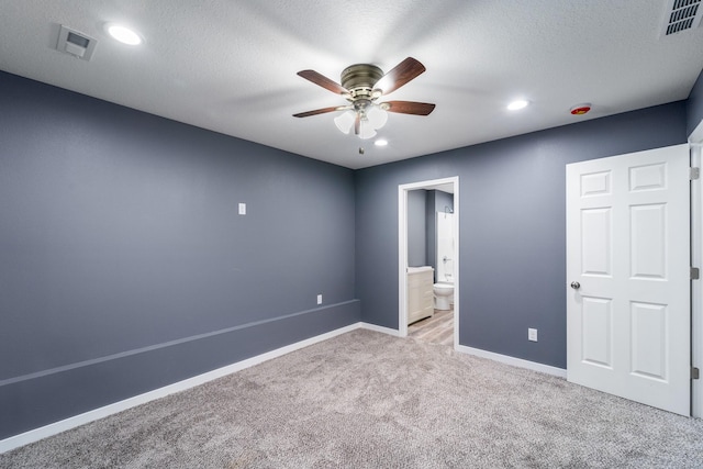 unfurnished bedroom with ceiling fan, light colored carpet, a textured ceiling, and connected bathroom