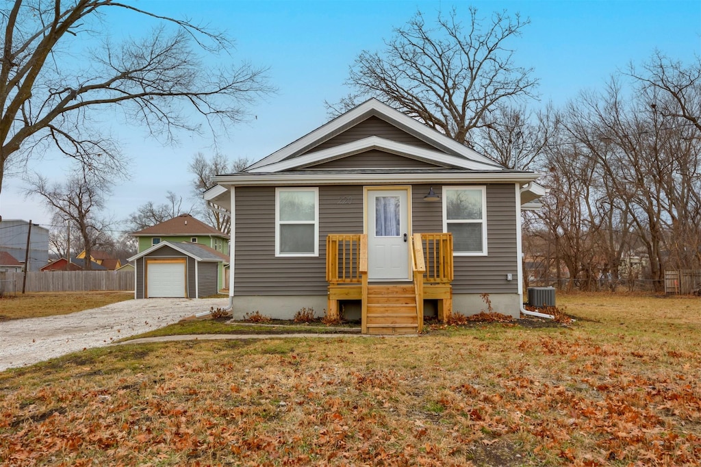 bungalow with cooling unit, a garage, an outdoor structure, and a front lawn