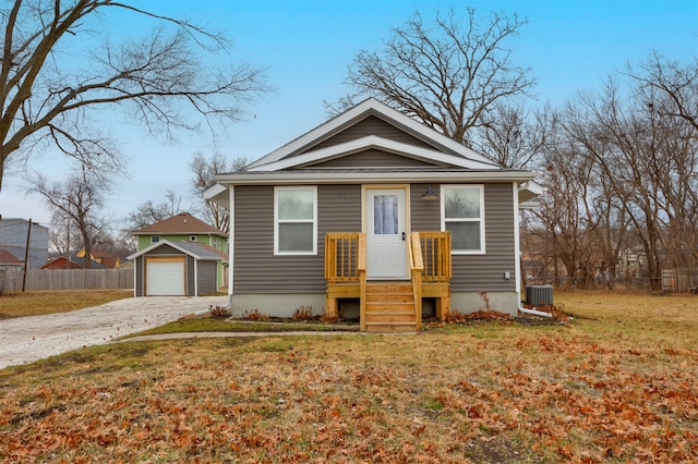 bungalow with cooling unit, a garage, an outdoor structure, and a front lawn