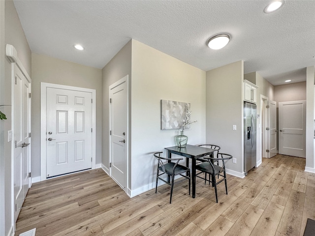 dining room featuring light hardwood / wood-style flooring and a textured ceiling