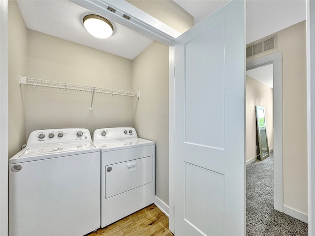 clothes washing area with light hardwood / wood-style flooring and washing machine and clothes dryer