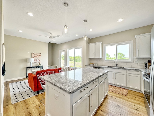 kitchen with white cabinets, a center island, a healthy amount of sunlight, and sink