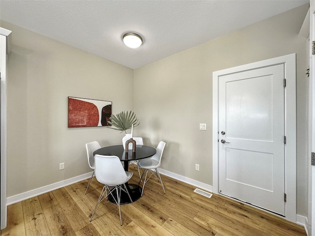 dining area with a textured ceiling and light wood-type flooring