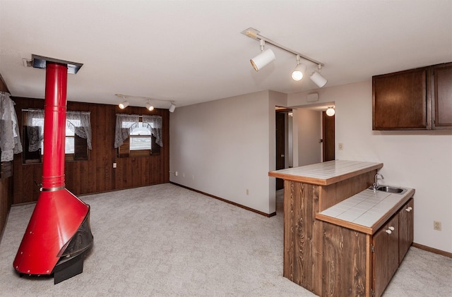 kitchen featuring light carpet, a sink, dark brown cabinetry, and tile counters