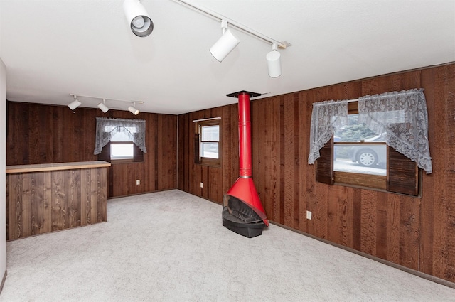 below grade area with a wood stove, carpet flooring, and wood walls