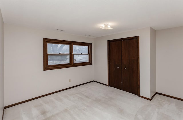 unfurnished bedroom with light carpet, visible vents, a closet, and baseboards