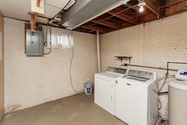 washroom with brick wall, electric panel, laundry area, tile patterned floors, and separate washer and dryer