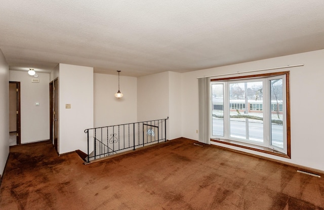 spare room featuring a textured ceiling and carpet flooring