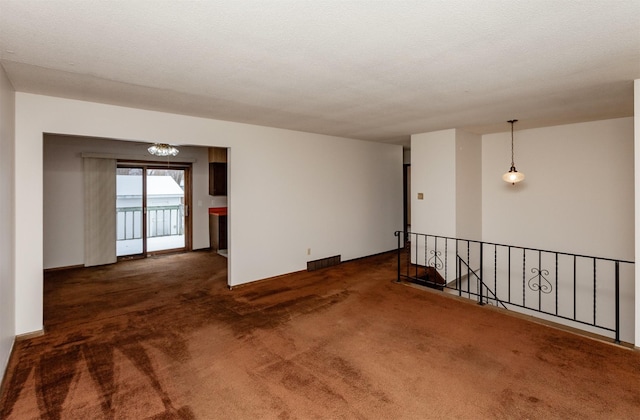 carpeted spare room featuring visible vents and a textured ceiling