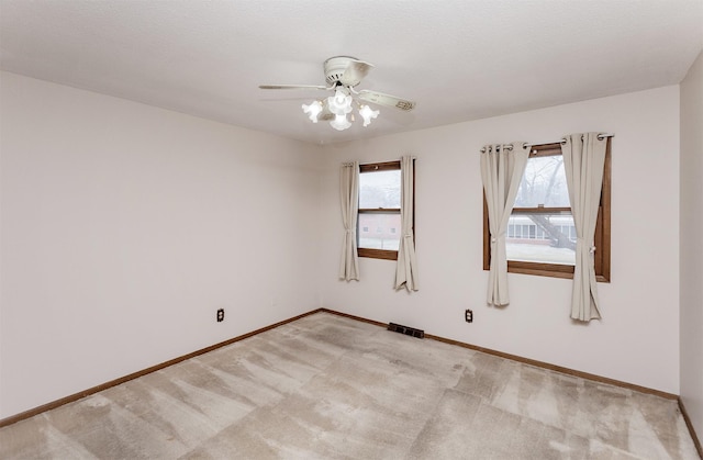 spare room featuring visible vents, light colored carpet, baseboards, and ceiling fan