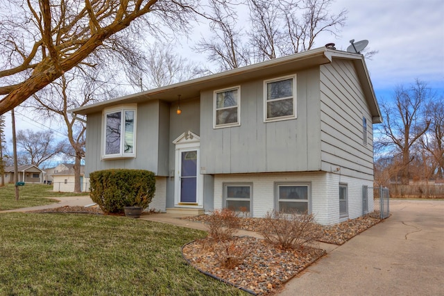 split foyer home with entry steps, brick siding, and a front lawn