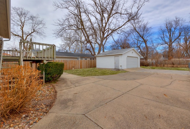 exterior space featuring an outdoor structure, fence, driveway, and a detached garage