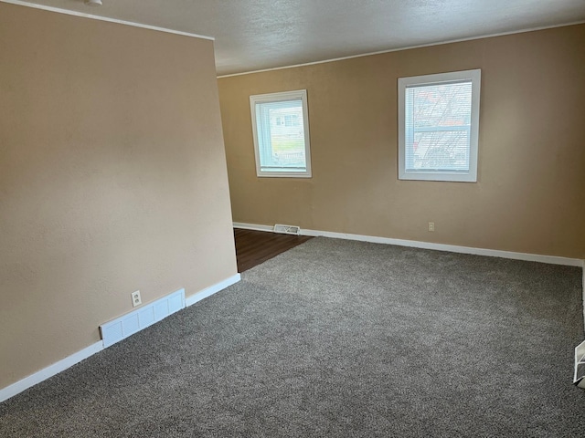 empty room with a textured ceiling and dark colored carpet