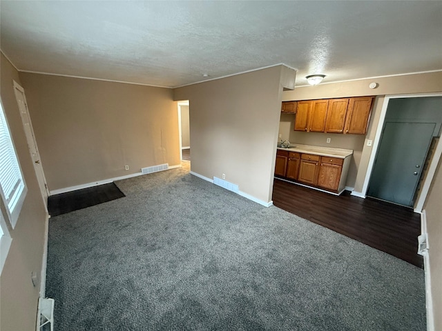 unfurnished living room with dark colored carpet, sink, and a textured ceiling