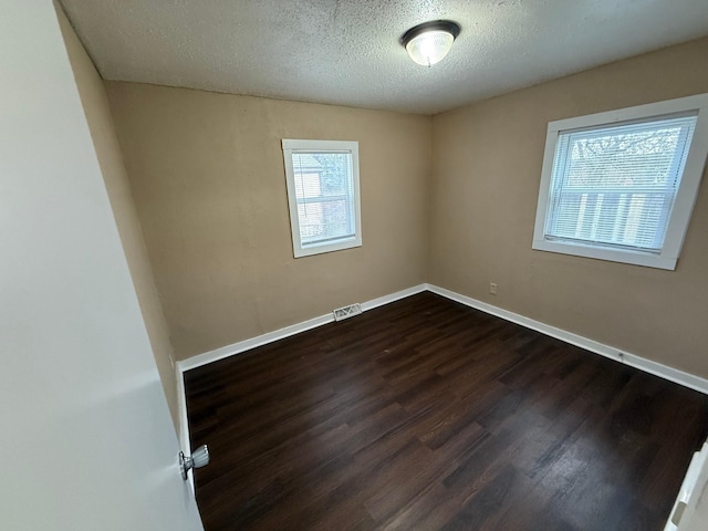 spare room with dark hardwood / wood-style floors and a textured ceiling