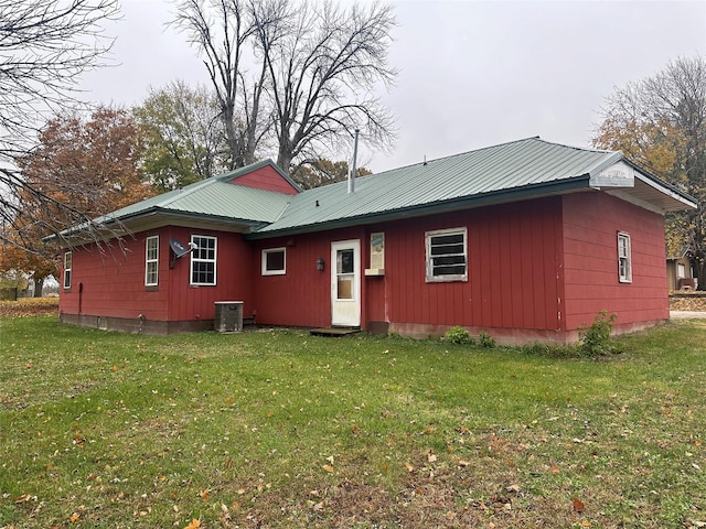 back of property with a yard and central AC