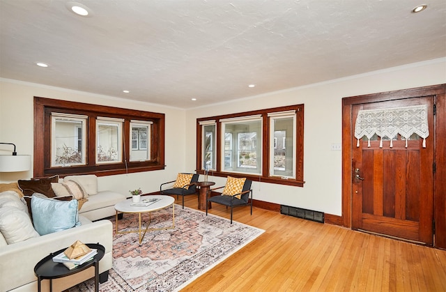 living room featuring ornamental molding, a textured ceiling, and light hardwood / wood-style flooring