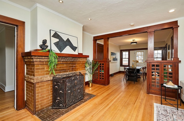 living room featuring ornamental molding, a brick fireplace, and light hardwood / wood-style floors