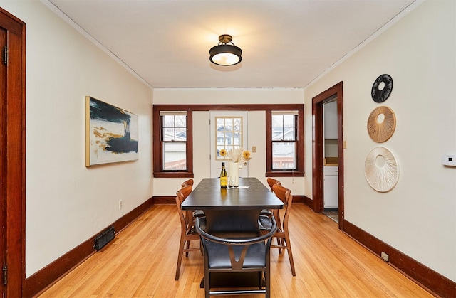 dining room with crown molding and light hardwood / wood-style flooring