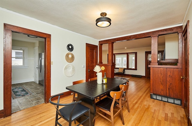 dining area with ornamental molding, light hardwood / wood-style floors, and a textured ceiling