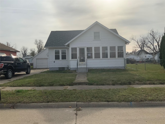 bungalow-style house with a garage, an outbuilding, and a front lawn