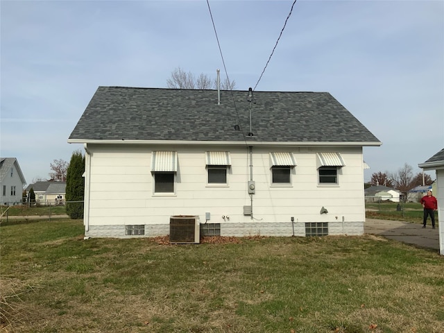 rear view of property with central AC unit and a yard