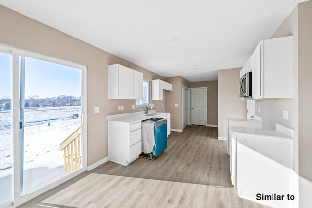 kitchen with appliances with stainless steel finishes, white cabinetry, sink, and light hardwood / wood-style floors