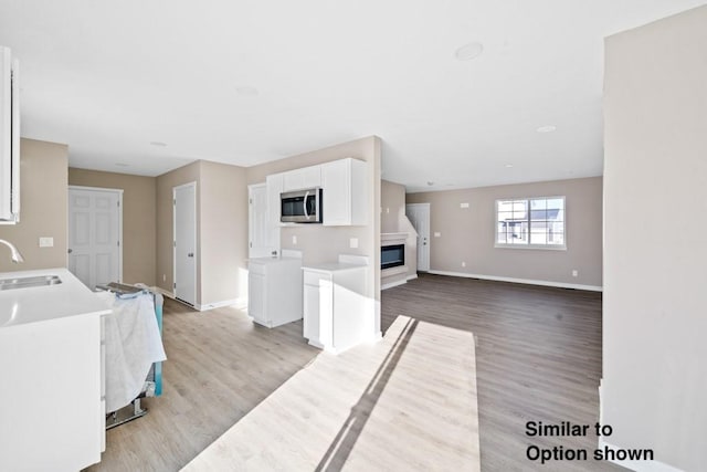 interior space with white cabinets, light hardwood / wood-style floors, and sink