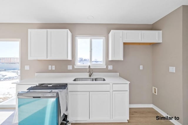 kitchen featuring white cabinets, stainless steel dishwasher, light hardwood / wood-style floors, and sink