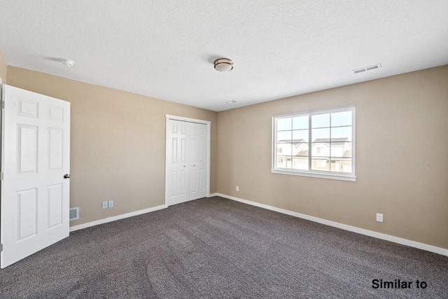 unfurnished bedroom with dark carpet and a closet