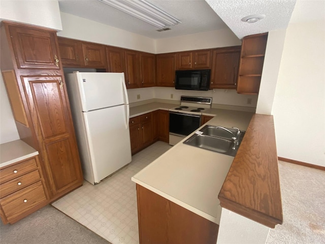 kitchen featuring a textured ceiling, kitchen peninsula, white appliances, and sink