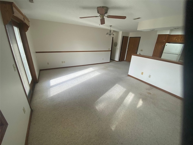 carpeted empty room featuring ceiling fan with notable chandelier