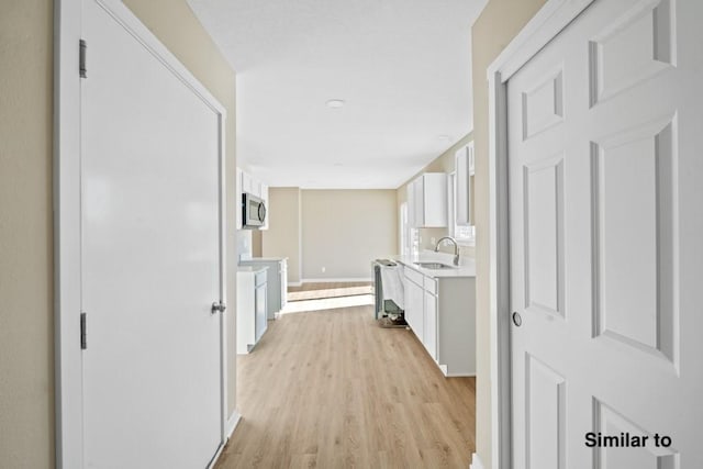 corridor featuring light wood-type flooring and sink