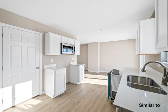 kitchen with sink, white cabinets, and light hardwood / wood-style flooring